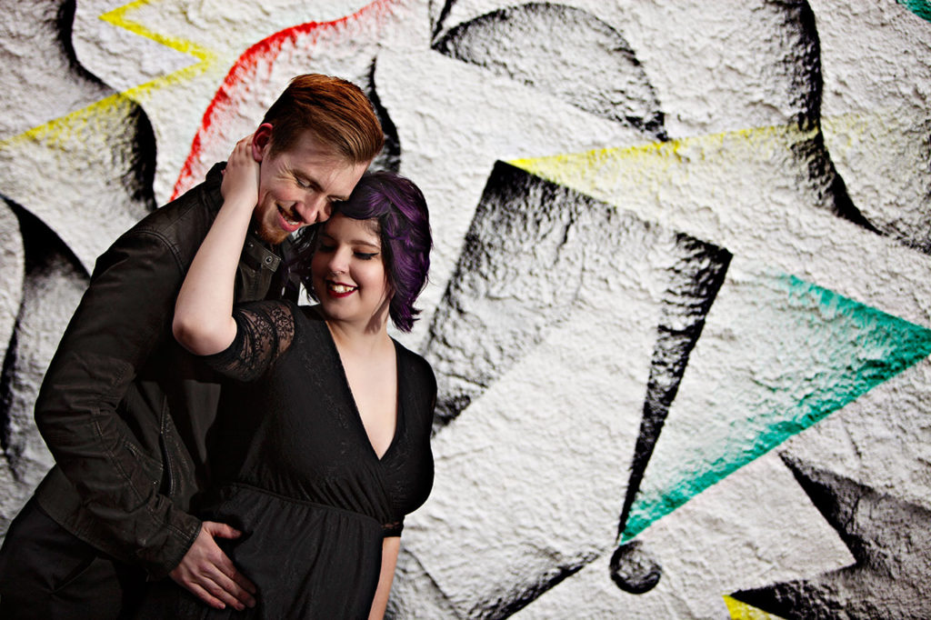 Couple smiling in front of graffiti wall